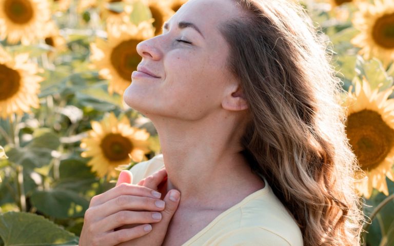 TheREDWords.website/BLOG page. A photo of a very happy woman in a field of sunflowers with her face to the sun.