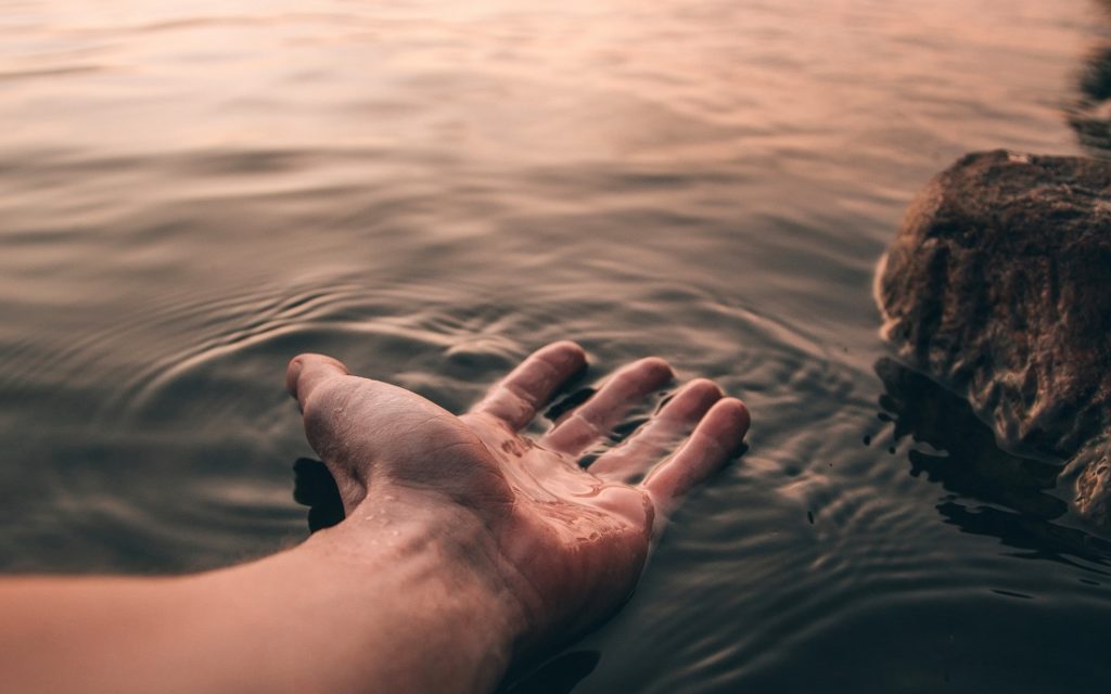 TheREDWords.website/BLOG page. A photo of a hand resting on the surface of a lake.