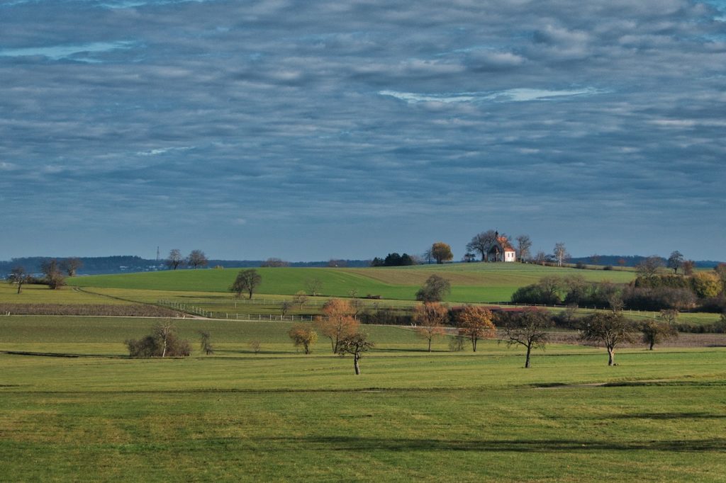 TheREDWords.website/BLOG page. A photo of the countryside and in the distance a small white church.