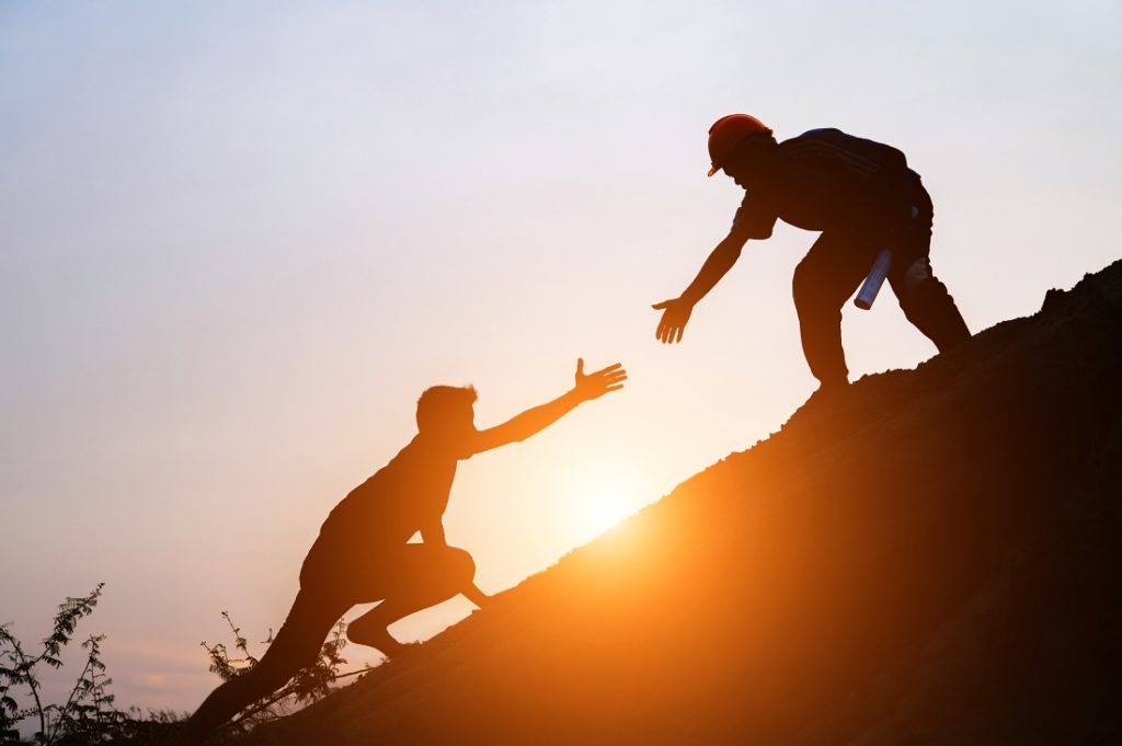 TheREDWords.website/BLOG page. A photo of a man in a hardhat reaching down to help another man out of a pit.