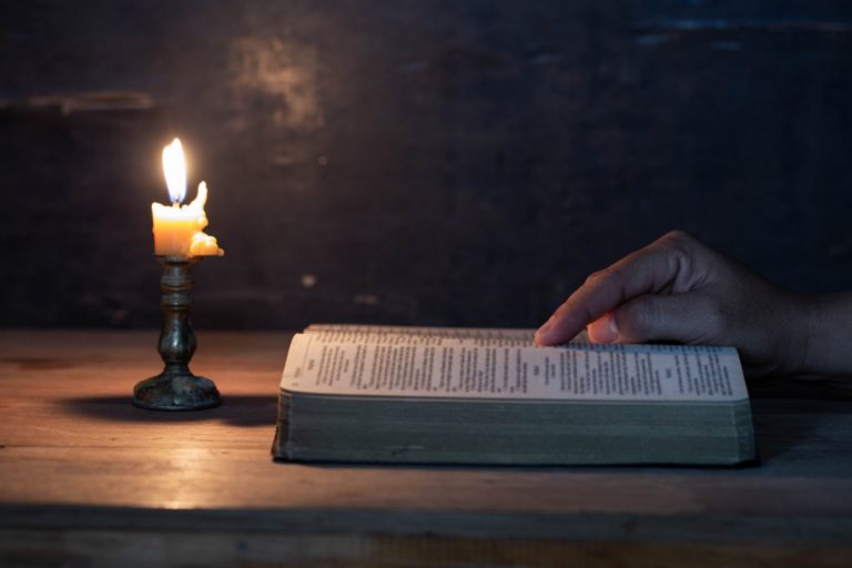 TheREDWords.website/BLOG page. A photo of the open Holy Bible in candlelight. A hand traces scripture.