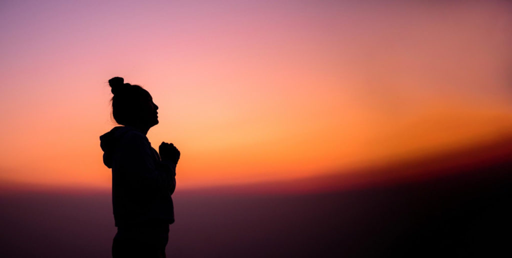 TheREDWords.website/BLOG page. A photo of a woman in prayer against the red sky at dusk.