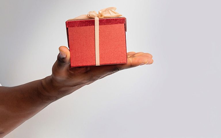 TheREDWords.website/BLOG page. A photo of a man's hand holding a gift box.