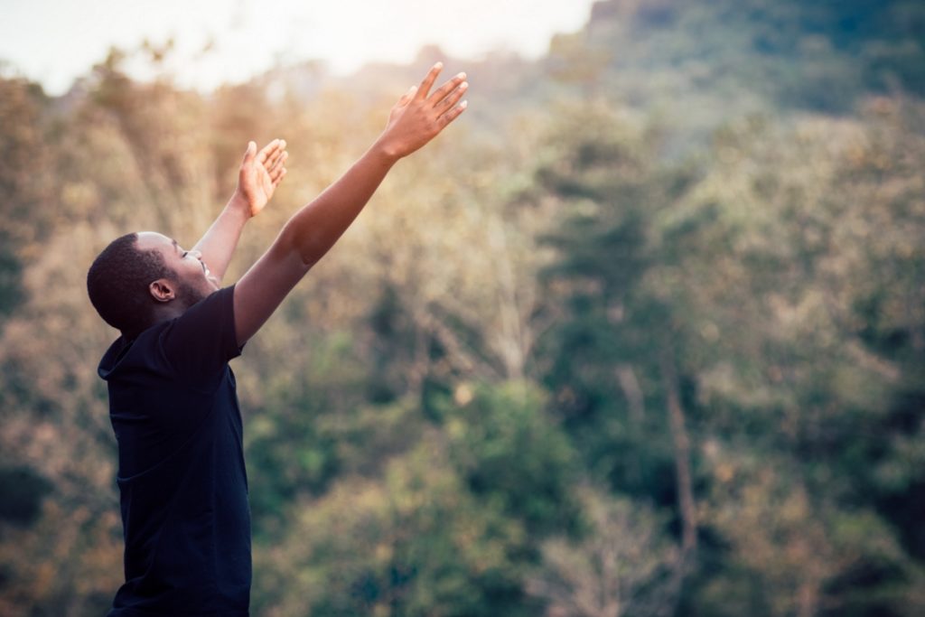 TheREDWords.website/BLOG page. A photo of a young man standing in a sunlit field worshiping.