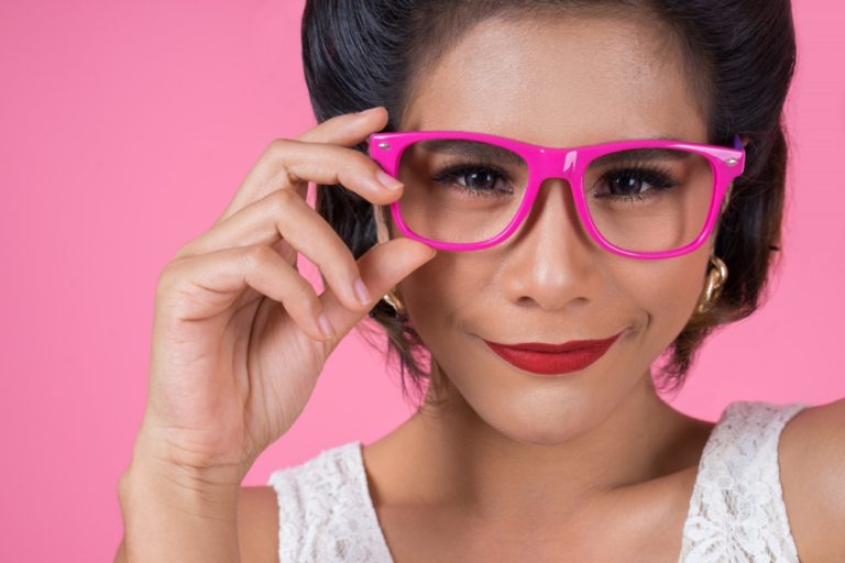 TheREDWords.website/BLOG page. A quirky photo of a young woman in bright pink glasses, smiling mischievously into the camera.