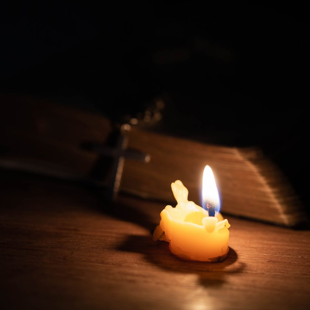 TheREDWords.website/BLOG page. A photo of a lit candle and a Bible in the dark.